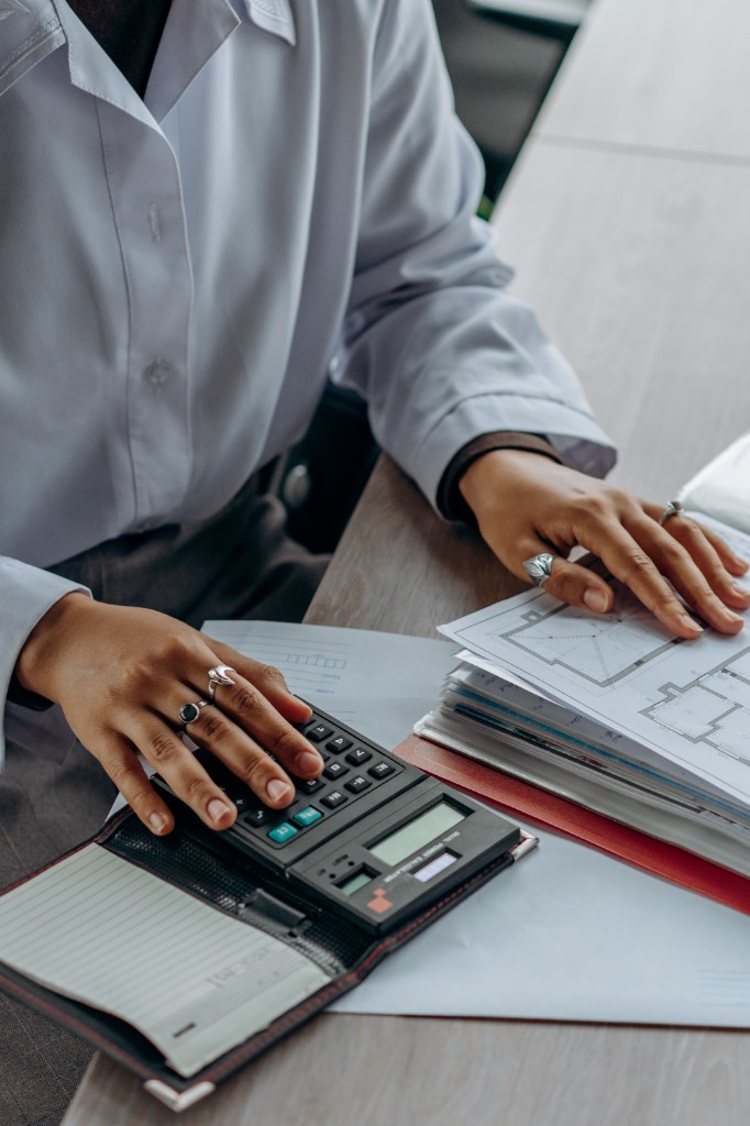 Professional reviewing floor plans and using a calculator at a desk